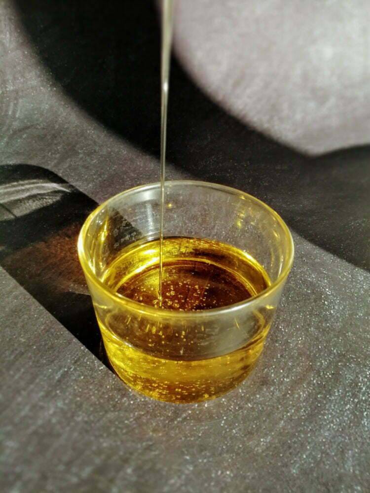 A small glass half filled with olive oil sits on top of a granite worktop