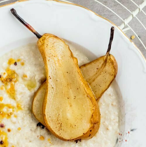 A dessert bowl of rice pudding with some dreid pear slices sitting on.  top. 