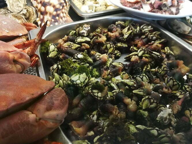 A large tray of seafood sits on ice in a fish market. 