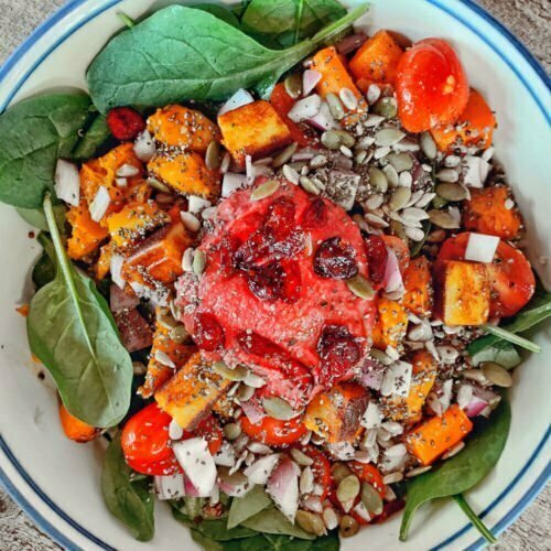 A bowl of plant based food sits on a rustic wooden counter, foods feature from the Mediterranean diet