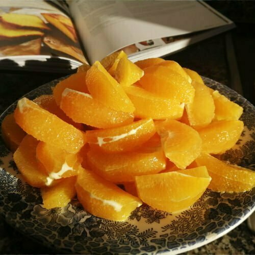 A plate of sliced and peeled oranges sits on an old patterned bowl in a Spanish kitchen