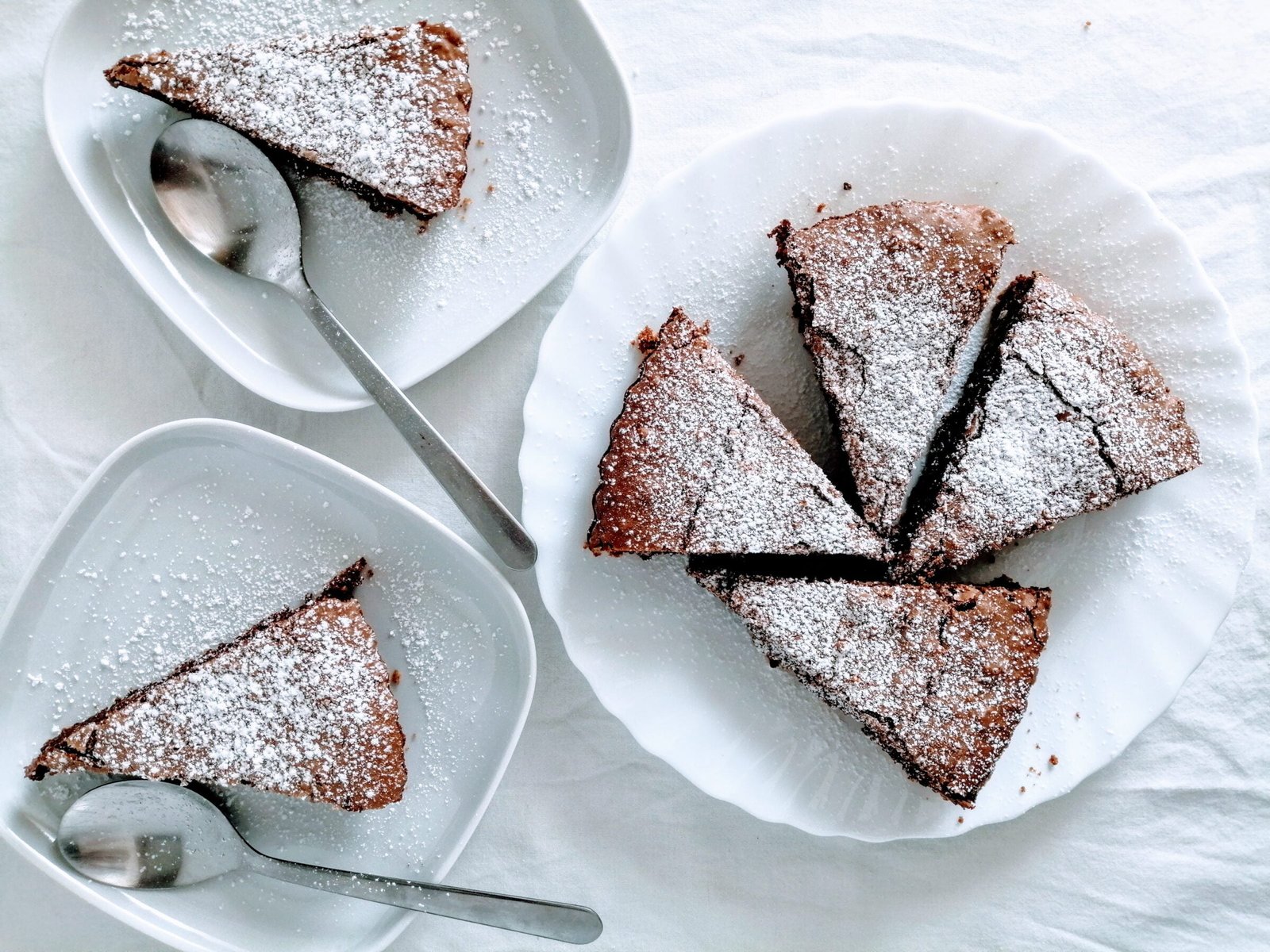 slices of chocolate hazelnut tart sit on white plates waiting to be served