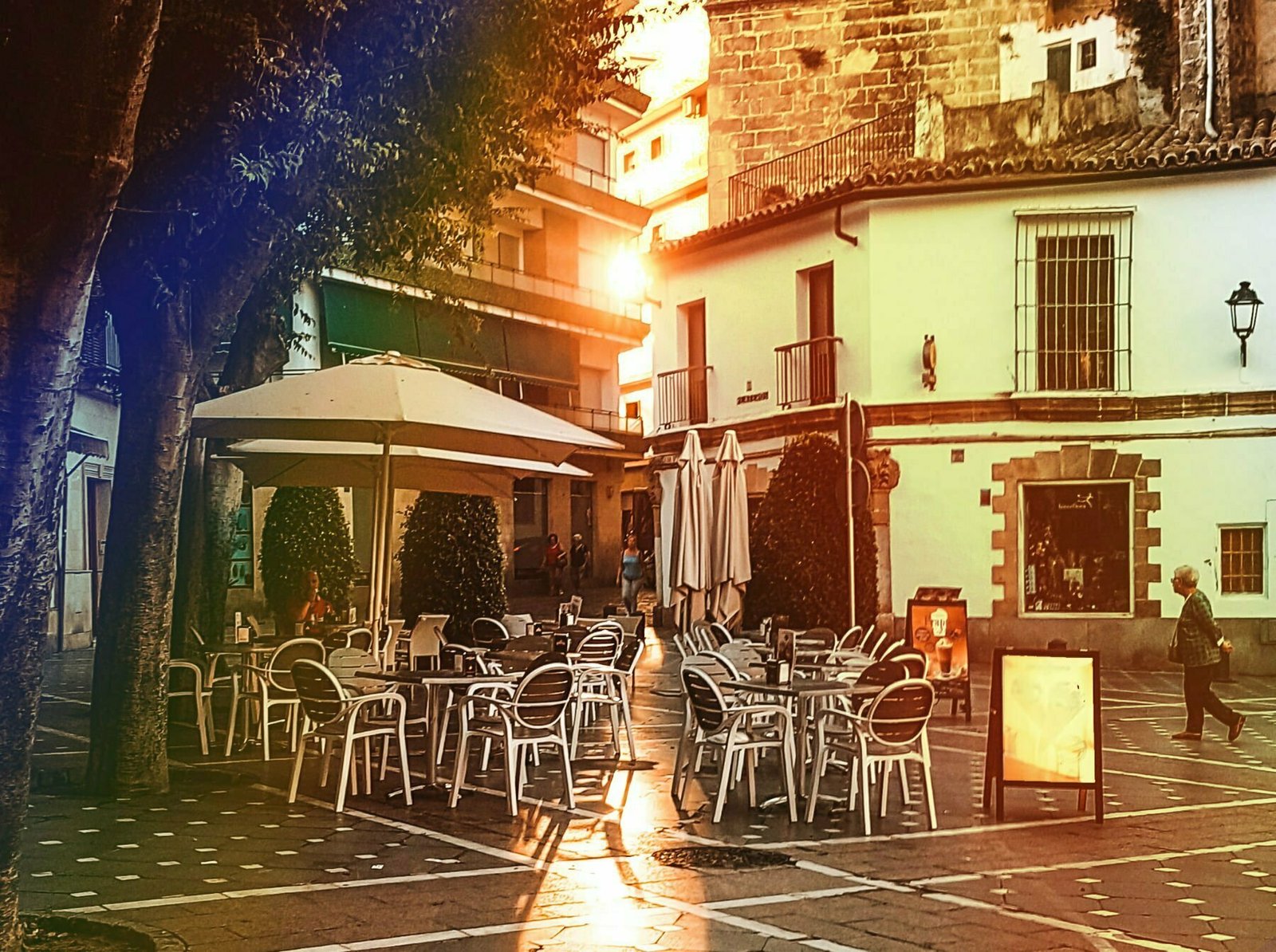 An andalusian plaza with a street bar and rays of afternoon sun streaming at the camera