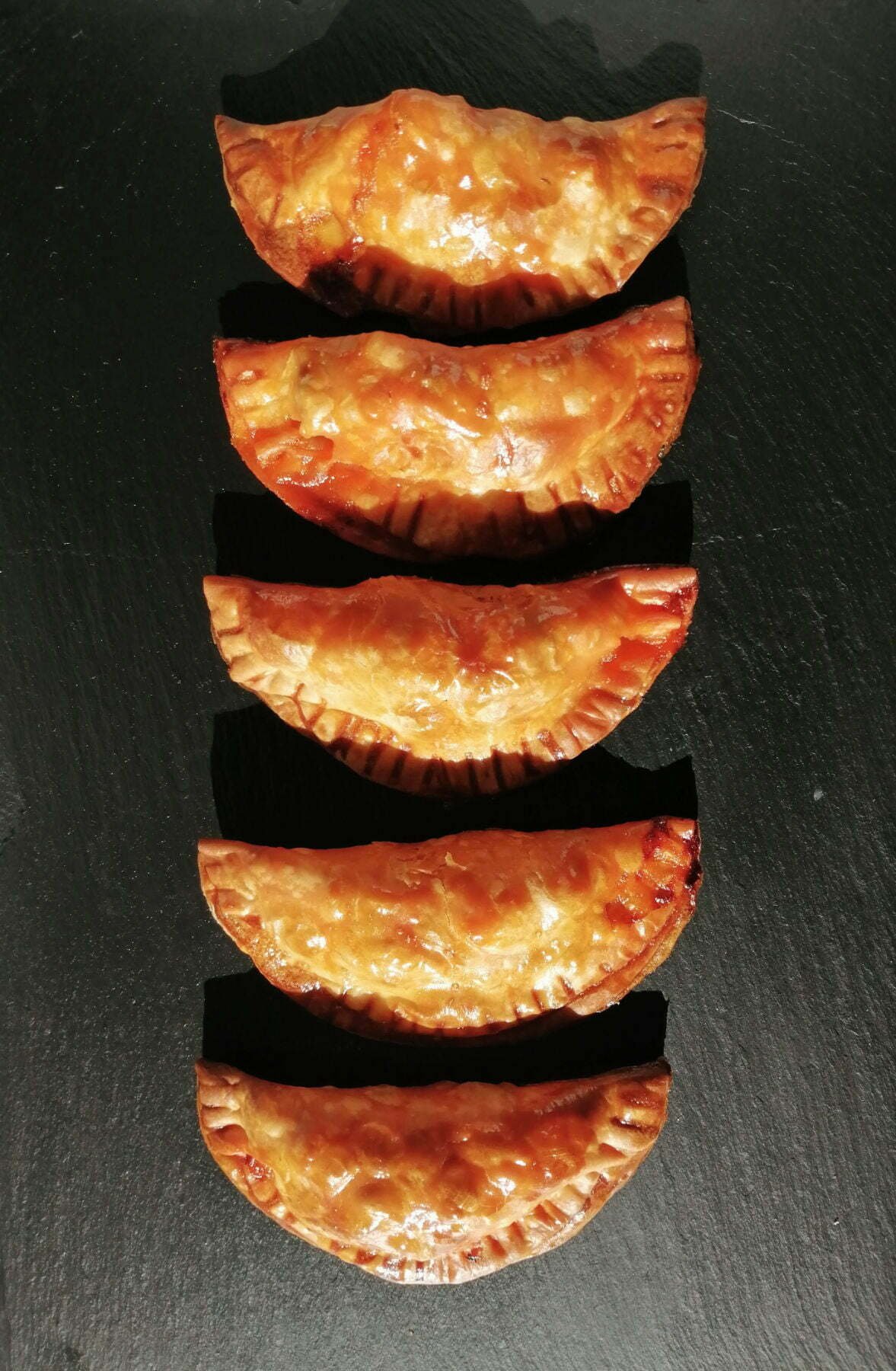 5 chicken with cider infused chorizo empanadas sit lined up on a slate plate