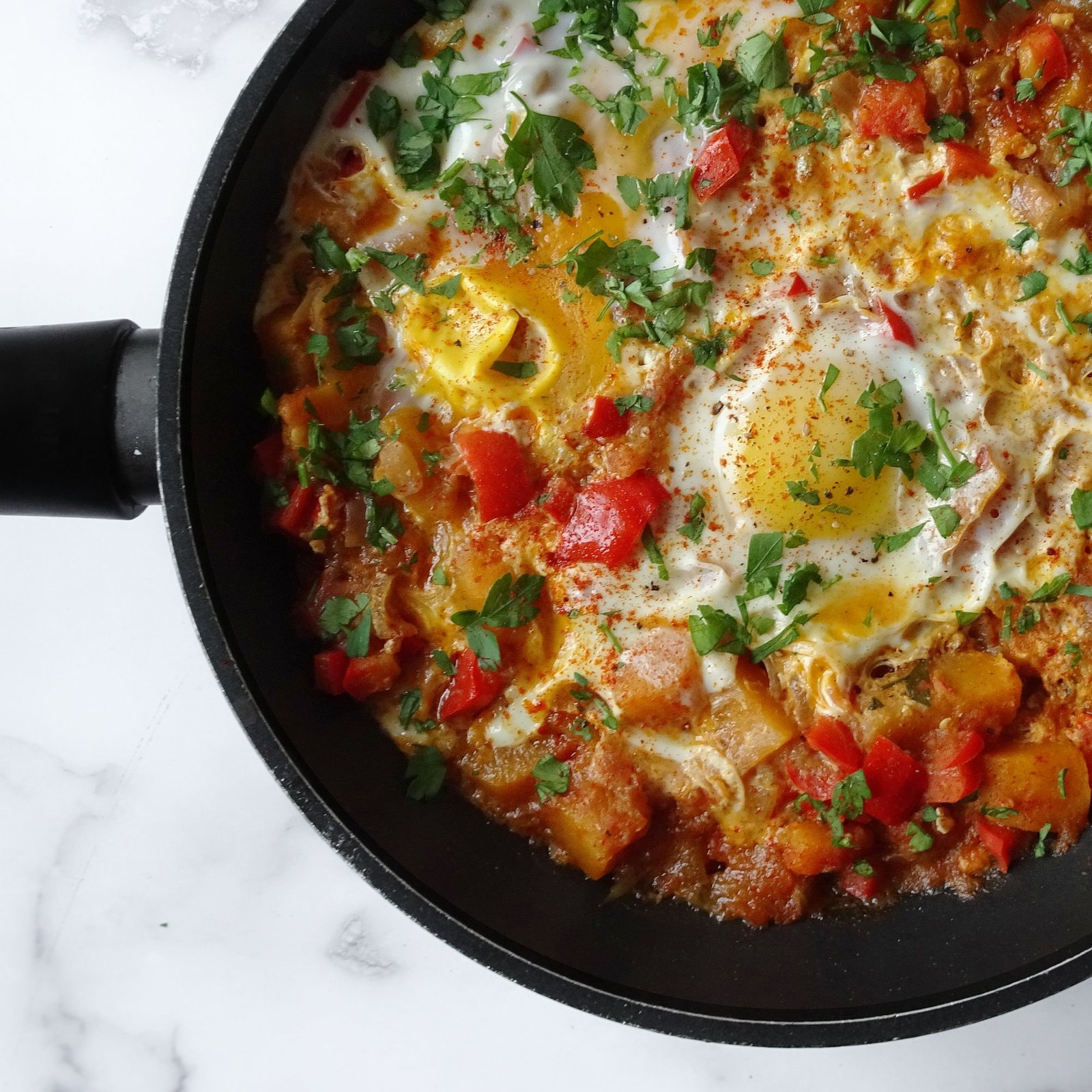 A frying pan of Spanish Vegetable Pisto with Eggs sits on a counter top