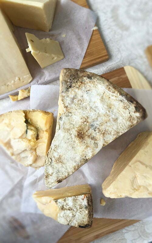 A cheeseboard of various Galician cheeses sits on a paper sheet waiting to be served. 