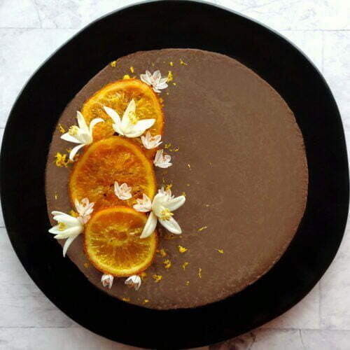 baked orange chocolate cheesecake is garnished with candied orange slices and some orange blossoms