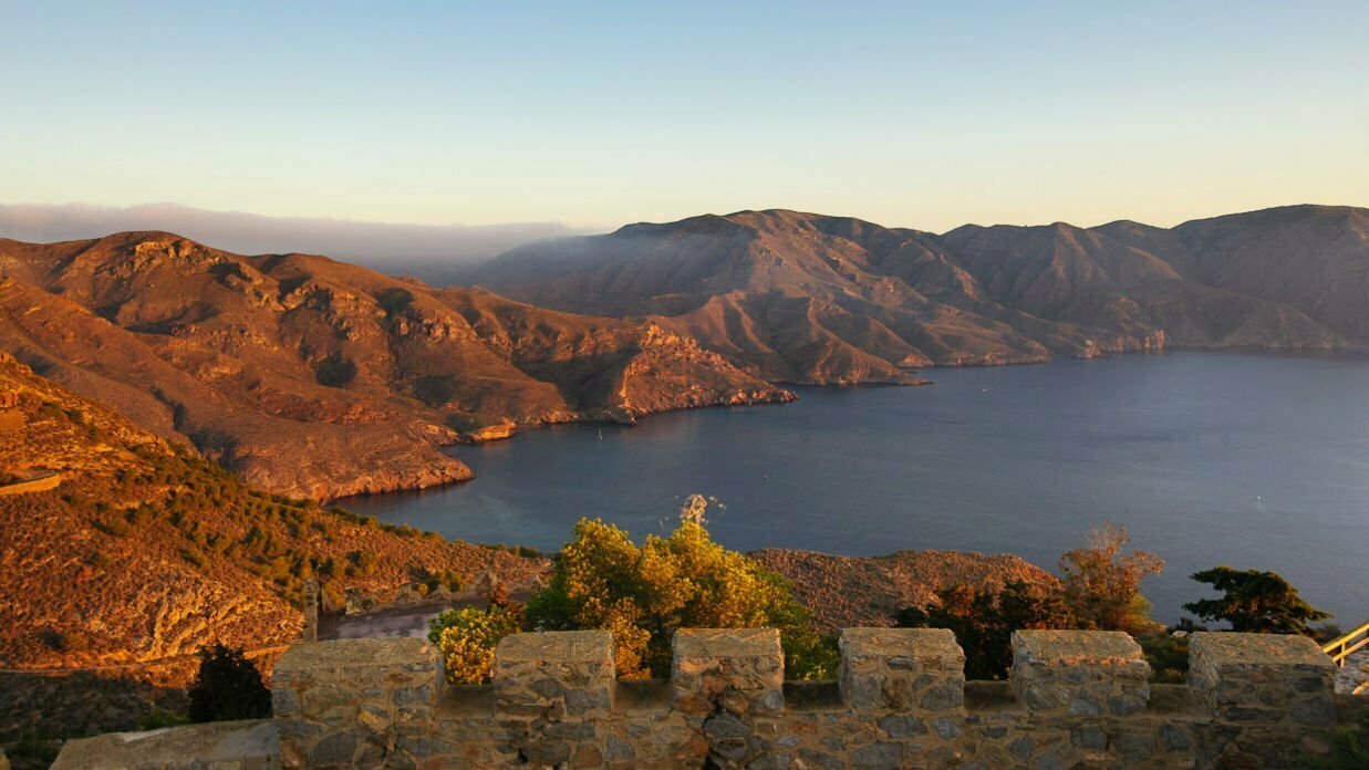 A sweeping landscape scene of some red mountains that recede into the sea along the Bateria de Castillitos