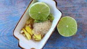 A small dish sits filled with some brown sugar, ginger, olive oil, and lime halves