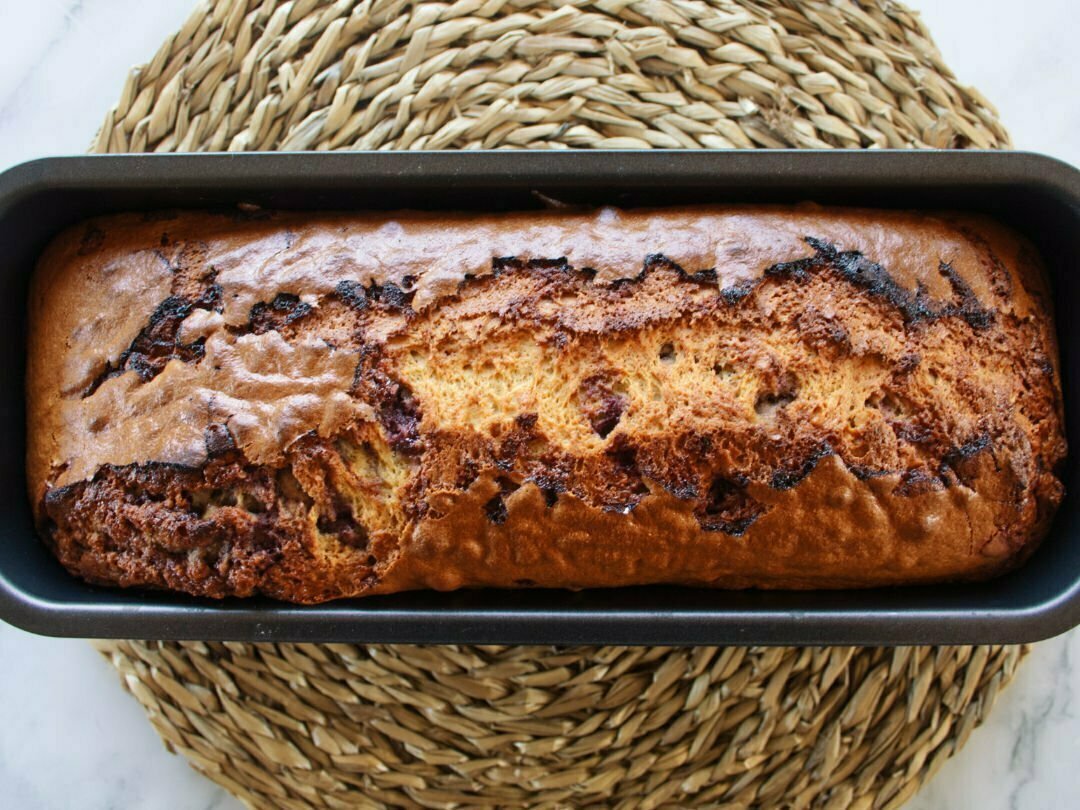 A freshly baked mulberry bizcocho sits in a cake pan waiting to be served