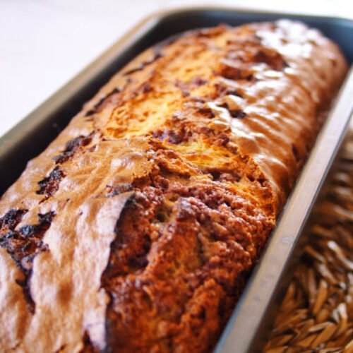 A freshly baked mulberry bizcocho sits in a cake pan waiting to be served