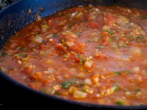 A tomato based sauce sits on a stovetop and simmers