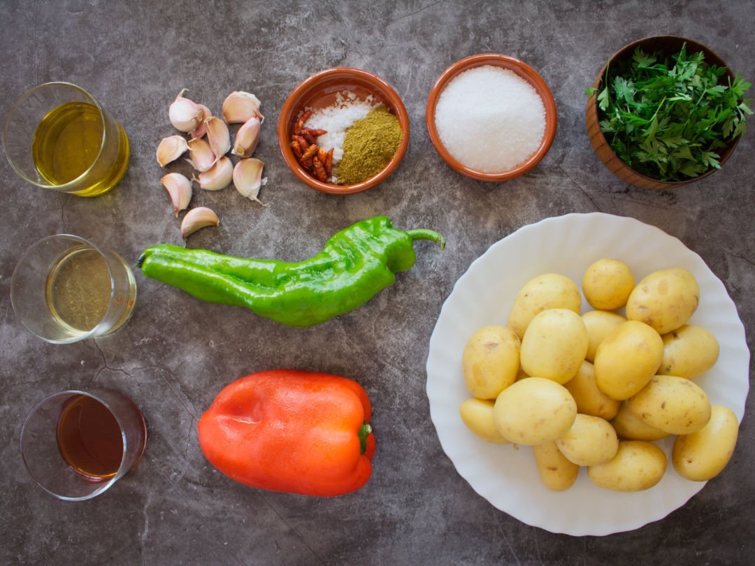 ingredients for papas arrugadas and mojo sauces are laid out. on a dark granite counter top. 