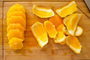 sliced orange with skin removed sits on a chopping board