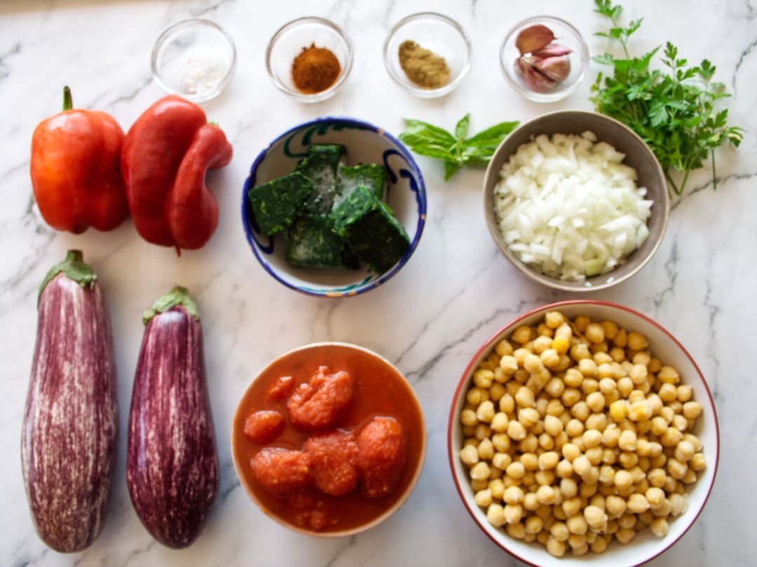 Mediterranean eggplant casserole ingredients are laid out on a white marble benchtop