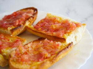 a large plate holds 4 slices of pan con tomate