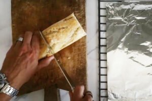 a large ciabatta is cut in half on a rustic chopping board