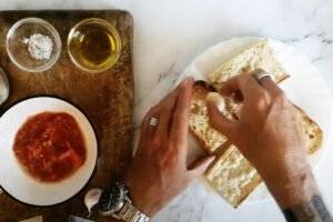 Some golden slices of toasted bread are being rubbed with a piece of garlic