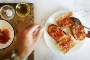 Grated tomato is added to some slices of toasted bread