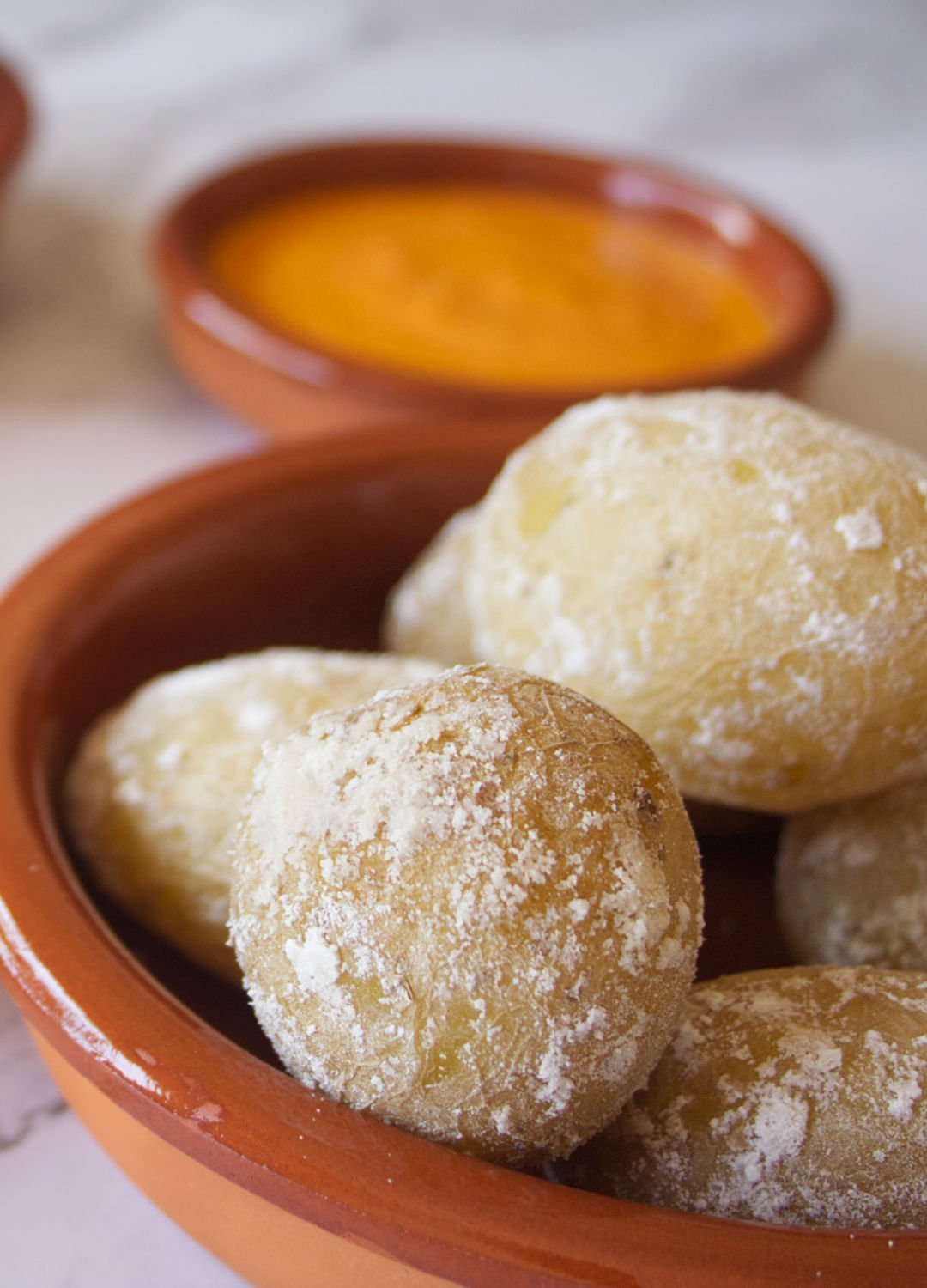 Small earthenware dishes filled with papas arrugadas, green mojo, and red mojo sauces.