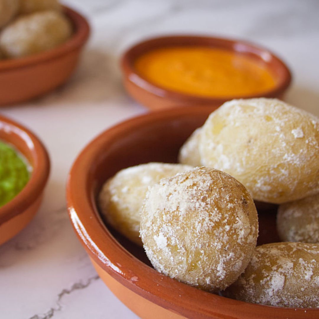 Small earthenware dishes filled with papas arrugadas, green mojo, and red mojo sauces.