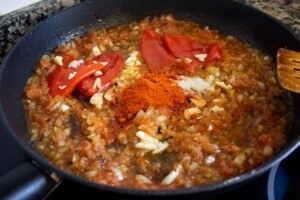 Some pepper, grates tomatoes, onion, and garlicc fry in a pan