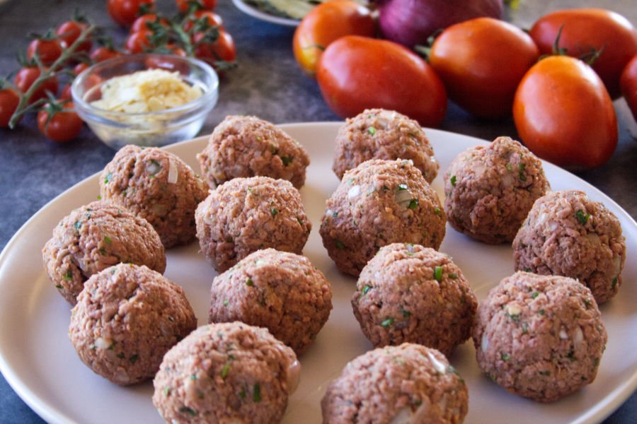 some freshly made vegetarian meatballs sit ona plate waiting to be cooked