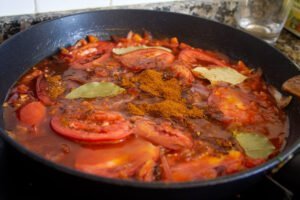 spices added to. sofrito sauce on a stovetop