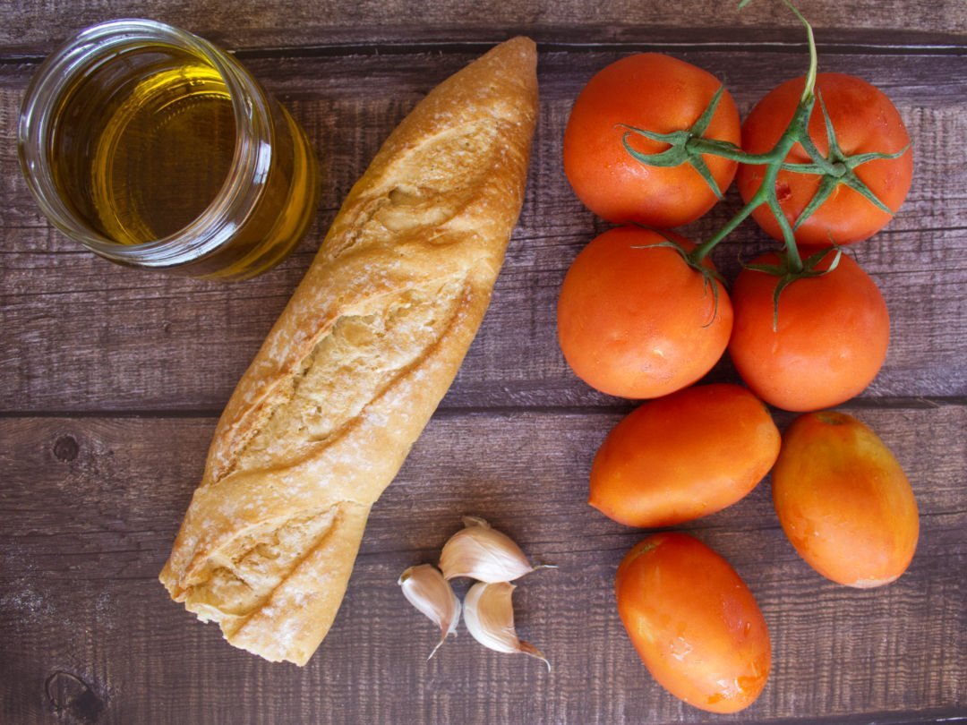 ingredinets for making salmorejo are laid out on a wooden countertop