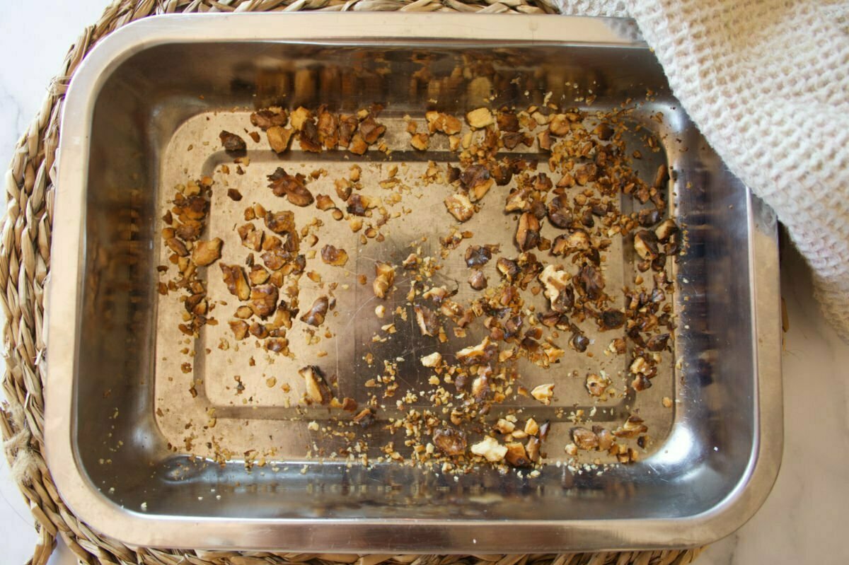 Some crushed and lightly toasted walnuts sit in a pan.