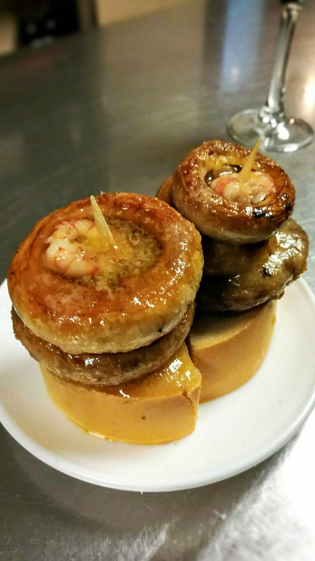 Some fried mushroom tapas sits on a small plate with a toothpick holding a stacck together. 