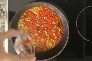 Some paprika is added to oil and garlic