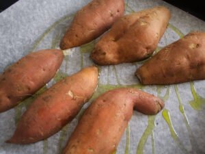 Sweet potatoes cut lengthways and placed skin side up in an oven tray with olive oil