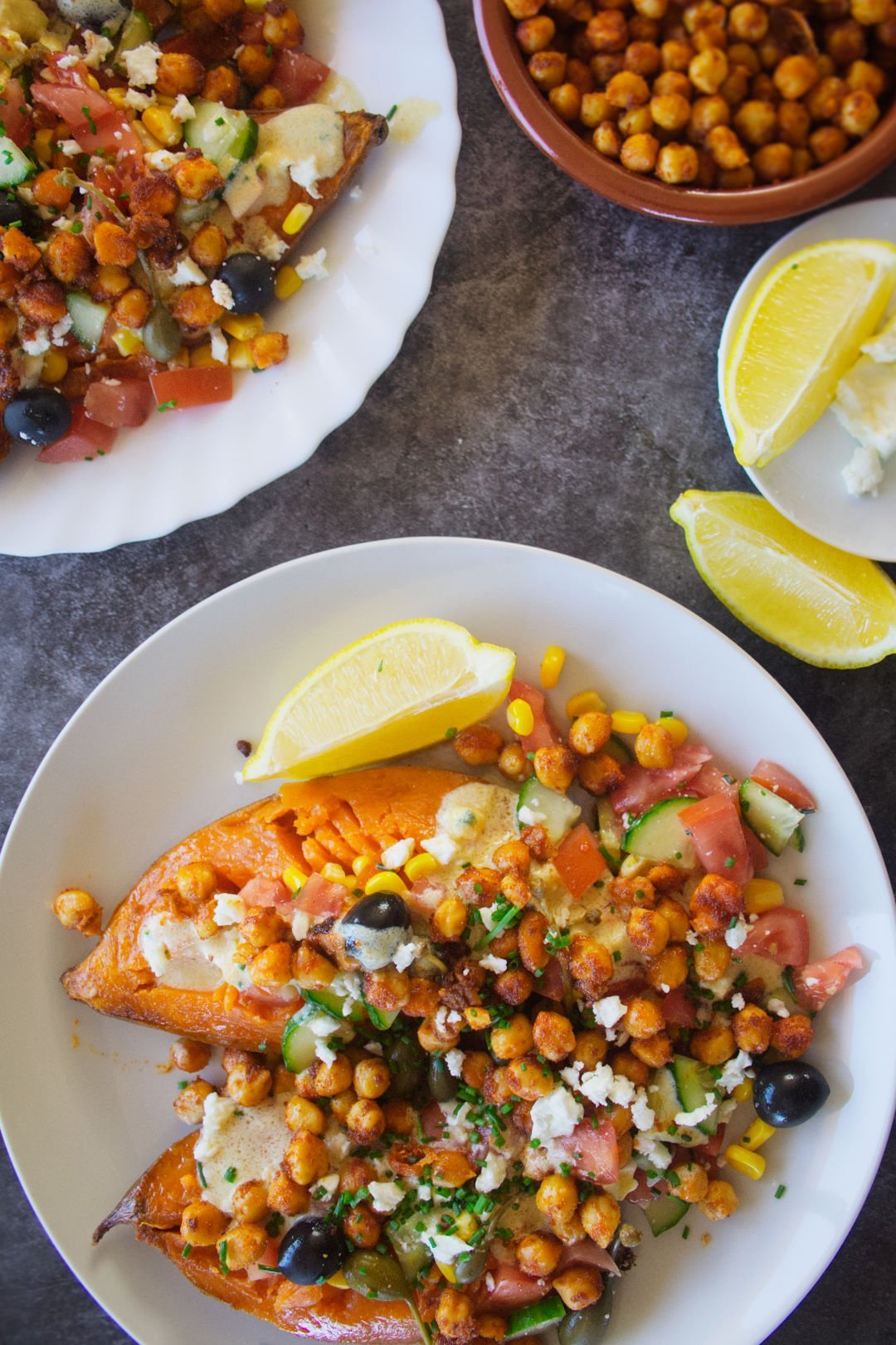 A few pates of Mediterranean baked sweet potatoes loaded up with toppings and a white yogurt sauce