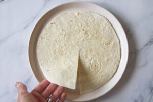 An organic flour tortilla sits with a small cut from 6 o'clock to the center.