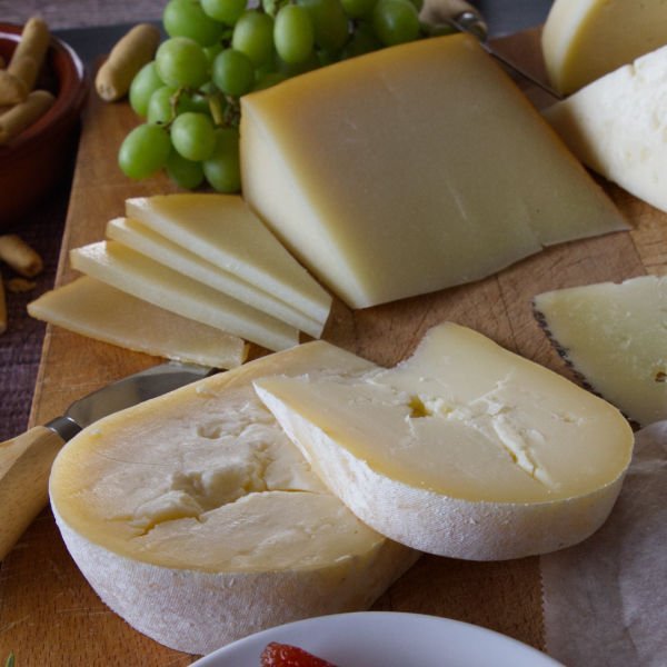 A platter of various types ofSpanish cheese sits beside some grapes