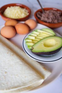 Vegetarian ingredients are laid out for making a toritlla breakfast wrap