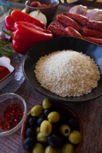 Some rice sits in a black bowl surrounded by other ingredients