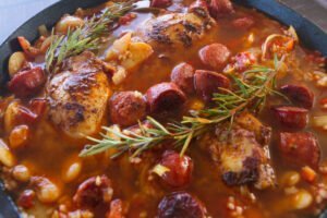 Stock is added to a pan of Spanish chicken and rice