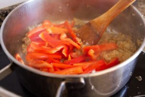 some onion, garlic, and red pepper simmer in a large pot