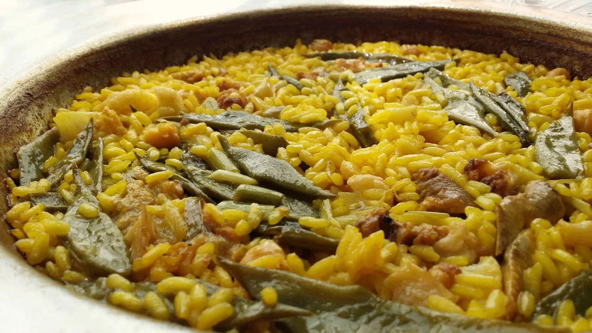 A large pan of paella Valencia sits on a counter top