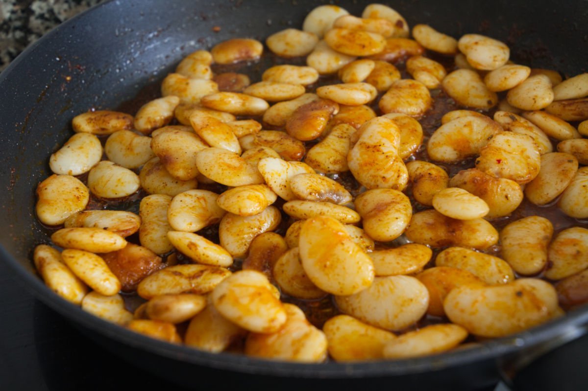 A pan of large white beans cooks in some chorizo oil