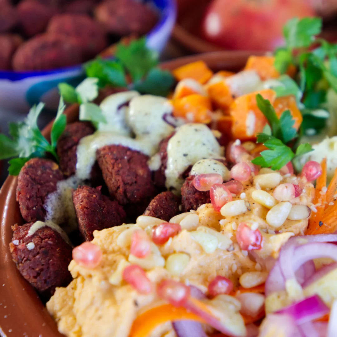 A beetroot falafel rice bowl sits with salad and other toppings.