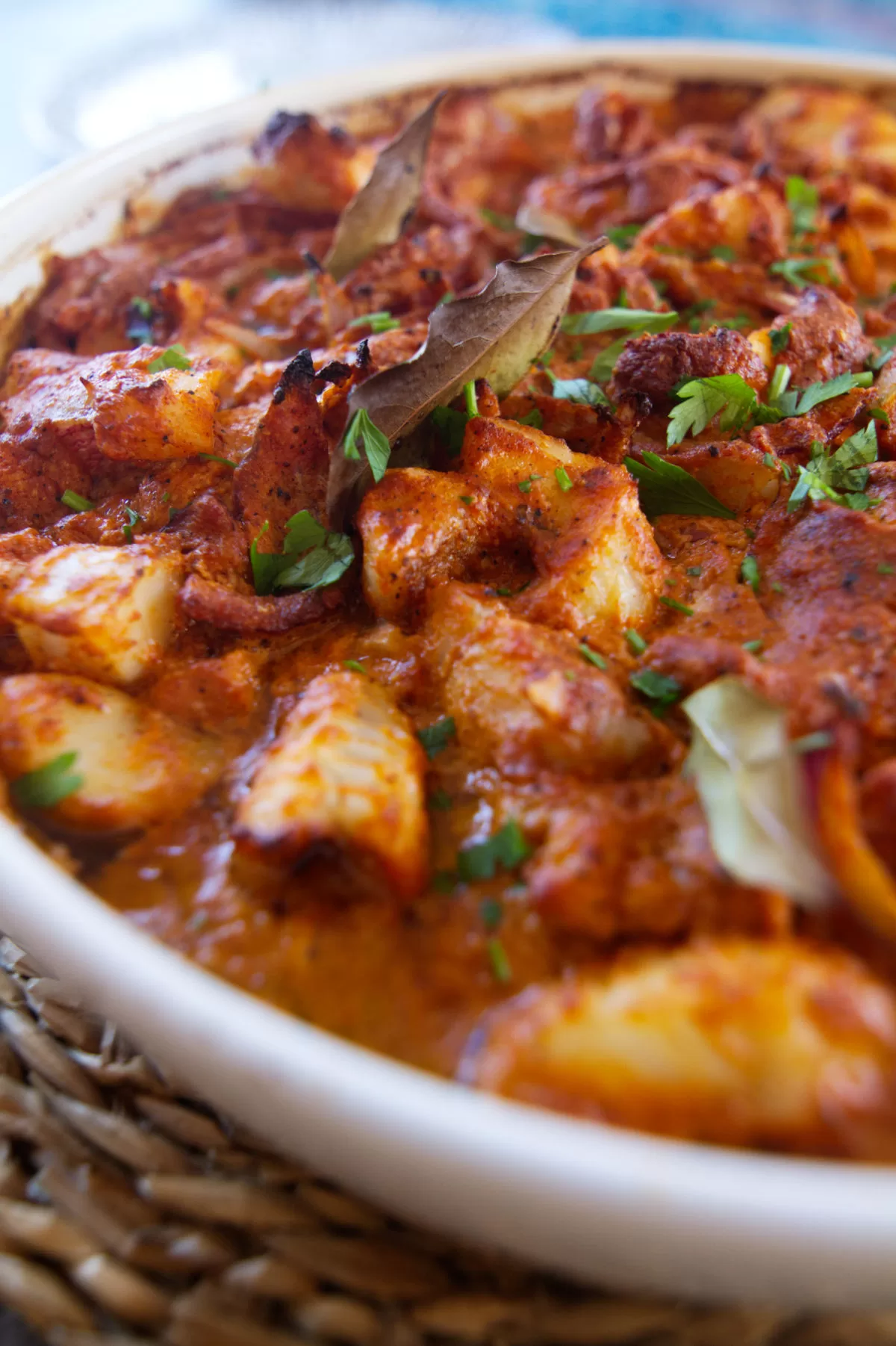 A large pot of romesco de peix with some bay leaves and parsley garnish