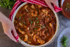 A large pot of Romesco de Peix is served beside some fresh sprigs of parsley