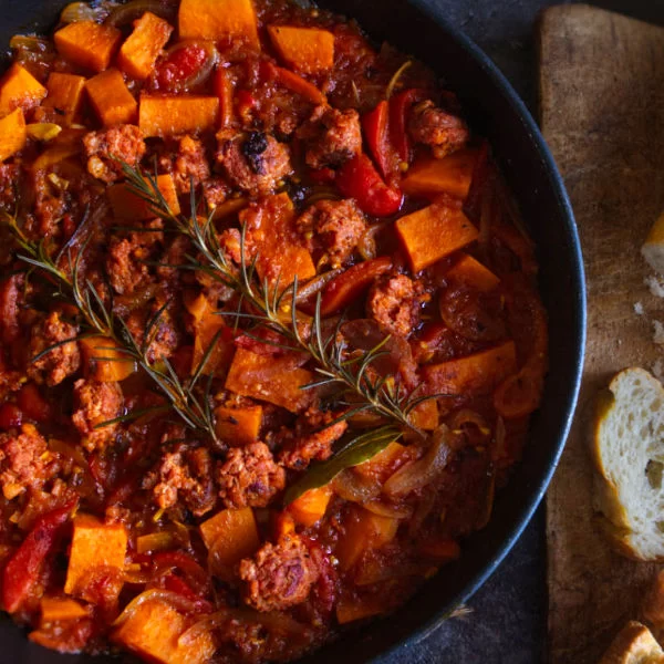 a large pot of smoky sweet potato chorizo stew sits beside some fresh bread