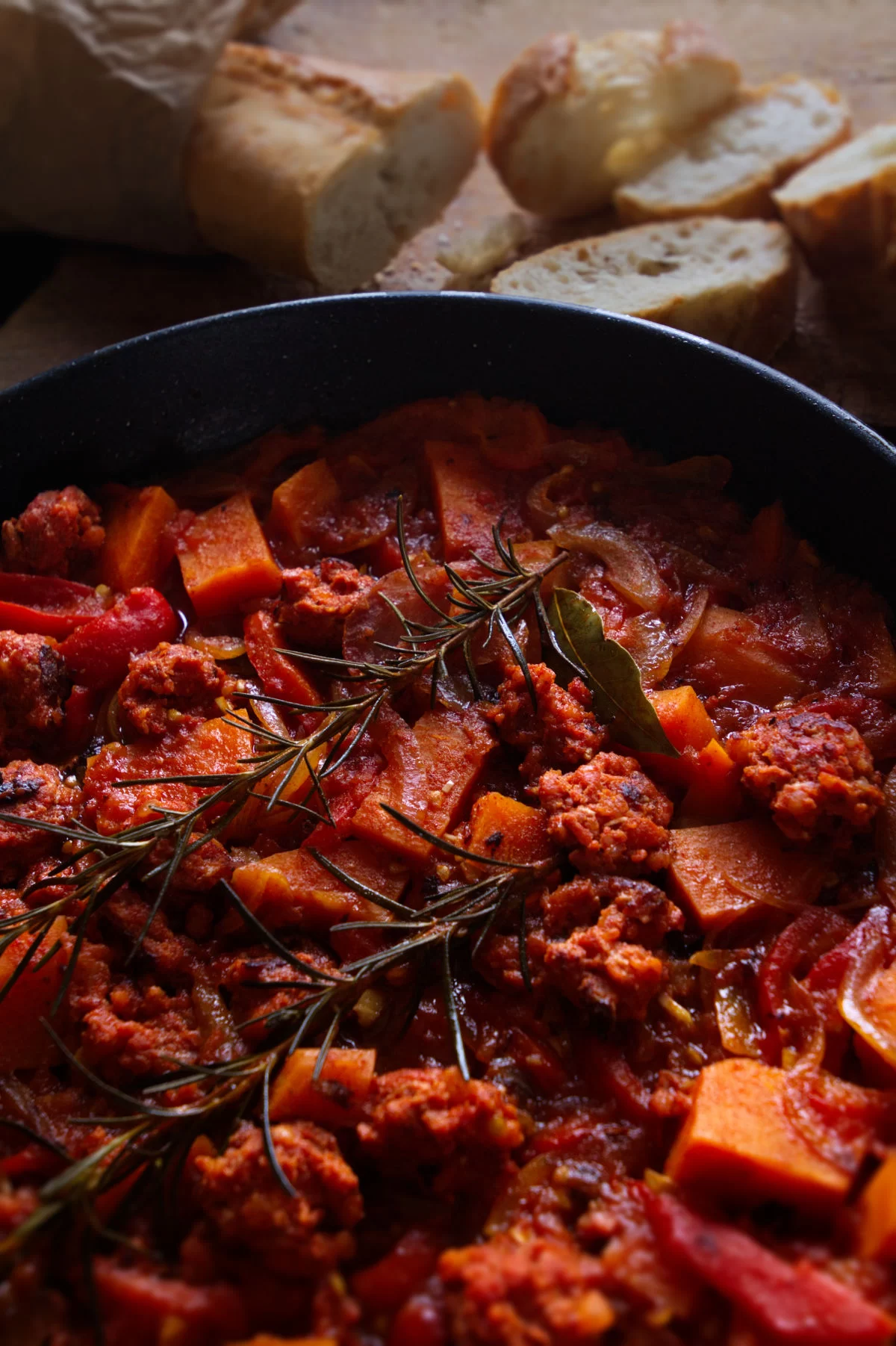 a large pot of smoky sweet potato chorizo stew sits beside some fresh bread