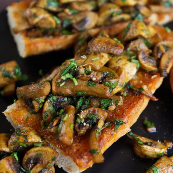 a plate of garlic mushrooms on a piece of toasted bread