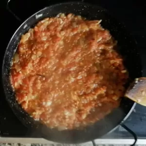 tomato is added to a pan of sauteed onions