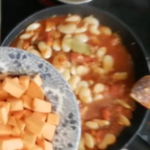 butter beans and diced sweet potato are added to a pan.